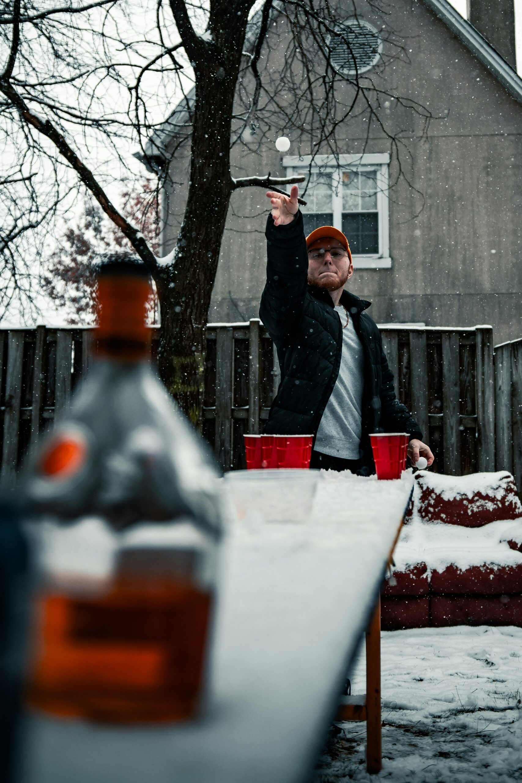 Fraternity student plays beer pong during party outside in the snow